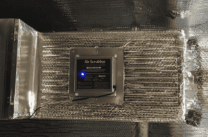 A trusted Air Scrubber with control panel and blue light, installed on reflective ductwork to boost your home's air quality.